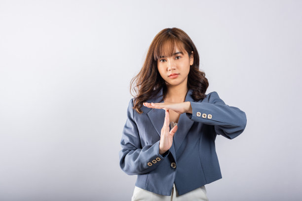 特写肖像年轻的女商人穿着西装，微笑着用手做时间的手势，工作室拍摄孤立的白色背景，示范中断手势，停止时间图片下载