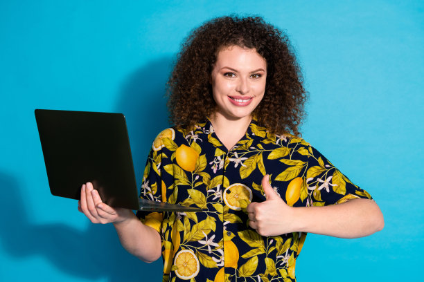 满意的可爱女孩穿着时髦的热带印花衣服的照片，在蓝色的背景上，拇指向上举起图片下载