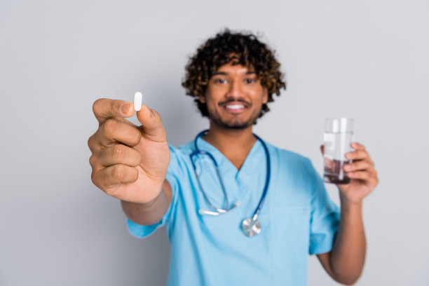 照片的医生盖伊建议药丸与水杯孤立的灰色背景图片下载