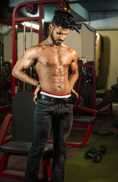 赤裸上身的健美运动员在健身房展示肌肉的照片。图片下载