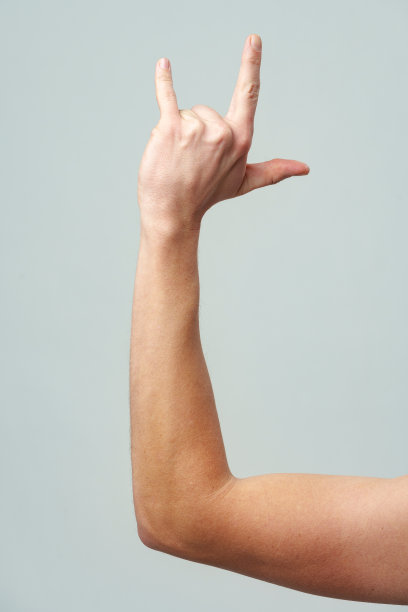 男性的手在灰色背景上做着摇滚乐的手势图片下载