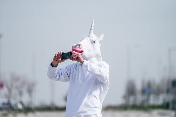 戴着独角兽面具的男子用智能手机拍照图片下载