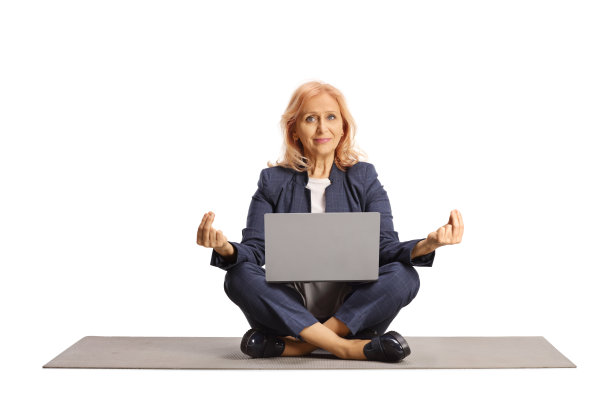 成熟的女商人拿着笔记本电脑坐在运动垫上冥想图片下载