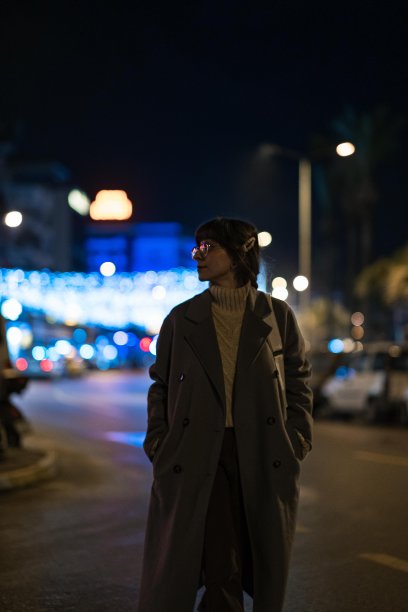 圣诞节走在街上的女人。背景中有夜晚城市灯光的散景图片下载