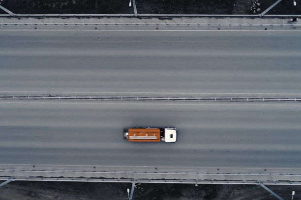 一辆装有橙色油箱的卡车正在过桥。图片下载