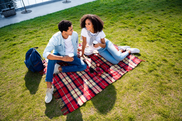 高角度观看两个友好的人的全尺寸照片，坐在毯子上喝咖啡，说话，寒冷，新鲜空气，户外公园图片下载