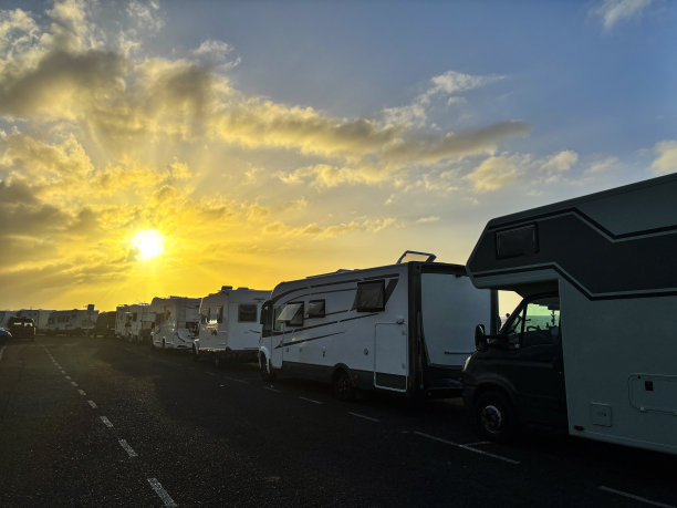 许多露营车、房车停在路上，日出日落的景色令人惊叹。另类旅行和度假的度假概念vanlife生活方式。乘坐现代休闲车旅行图片下载