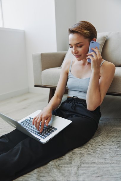 一个拥有笔记本电脑和手机的自由职业女性，穿着家常的衣服，剪着短发，坐在地板上工作，有自由的复印空间图片下载