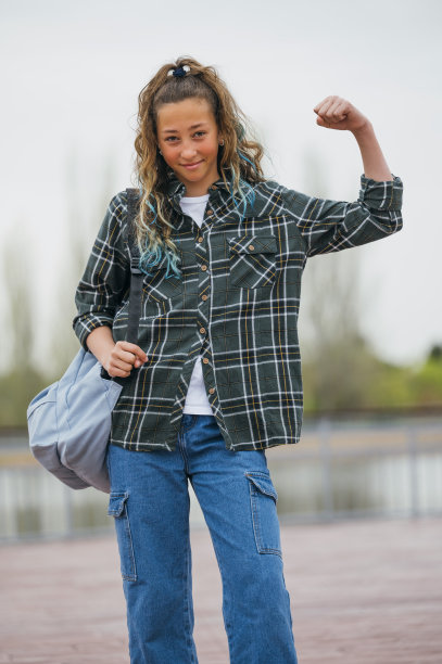一个十几岁的女孩背着背包去上学，看着镜头。图片下载