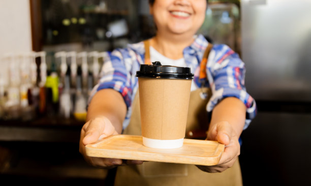 亚洲咖啡师女性60多岁高龄母女俩退休后开心地决定开咖啡馆咖啡店小生意创业，服务员工人正拿着一杯咖啡看着镜头图片下载