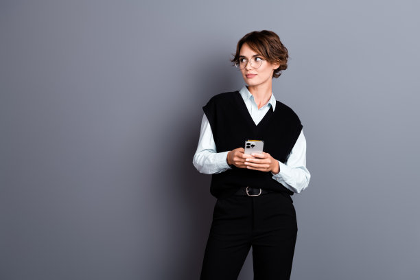 照片中，迷人自信的女人穿着时尚的黑色衣服，看起来空荡荡的宣传横幅孤立在灰色背景上图片下载