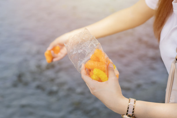 喂鱼。亚洲妇女双手拿着鱼食，给河里的许多鱼吃。图片下载
