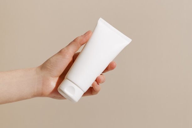 女性手拿白色奶油管模型在米色孤立的背景。美容的概念，美学和日常护理的皮肤的脸，身体和手。图片为您的设计。图片下载