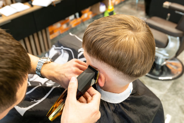 一个金发碧眼、满脸雀斑的孩子的照片在一家理发店的美容院里。磨坊主手里拿着一把铣刀。图片下载