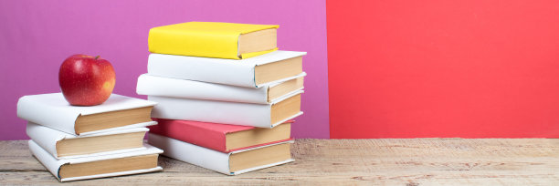 书堆积。书在木桌和红色，紫色的背景。回到学校。广告文本的复制空间。全景,旗帜。图片下载