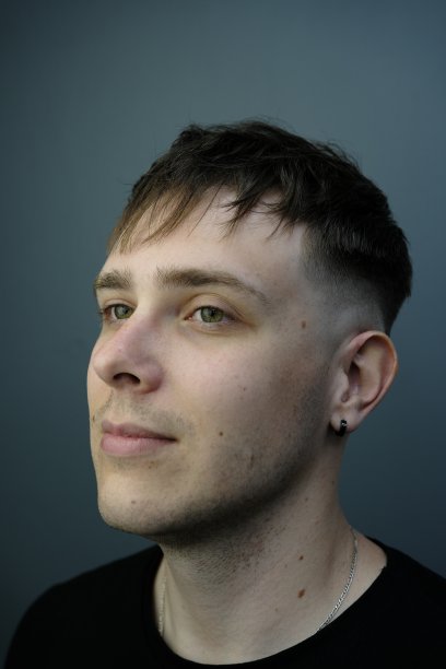 年轻男子的侧视图孤立的灰色背景与新鲜的发型。顾客理发后的理发店照片图片下载