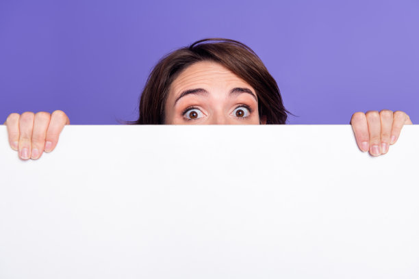 照片肖像的迷人的年轻女子背后的白色空白空间偷看穿着时尚的绿色衣服孤立的紫色背景图片下载