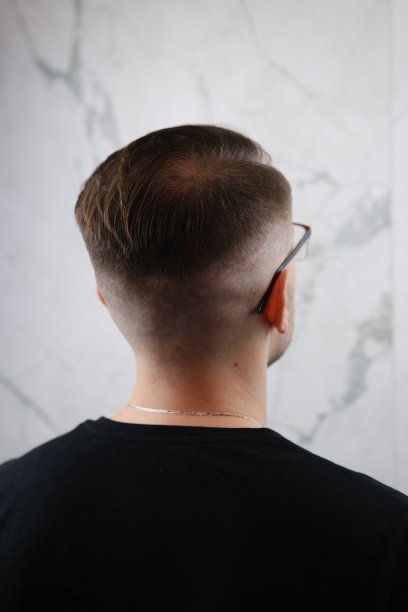 男性美的概念。这是一个发型时髦的年轻人，戴着时髦的眼镜，穿着时髦的t恤，在灰色的背景下摆姿势。完美的头发。Copy-space。影棚拍摄图片下载