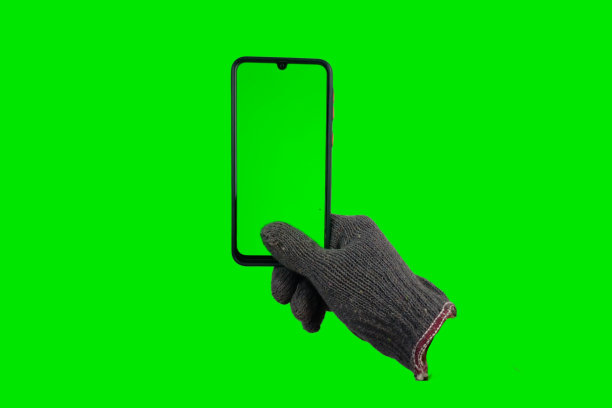 手套拿着绿色屏幕的智能手机。孤立的绿屏背景图片下载
