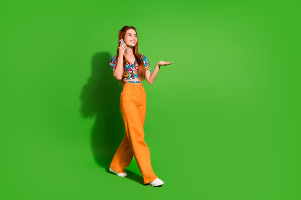 照片肖像迷人的年轻女子走路说话电话穿着时尚复古的衣服孤立的绿色背景图片下载