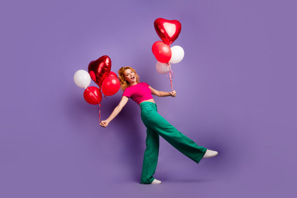 照片中，开朗积极的女性穿着时尚的粉色衣服，背着氦气球，在紫色的背景下独自参加派对图片下载