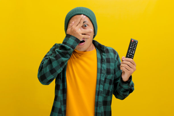 害怕的年轻亚洲人看恐怖电影从他的手指偷看图片下载