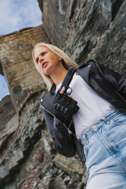 美国经典手枪M1911在一个金发女孩的手在户外。垂直的照片。图片下载