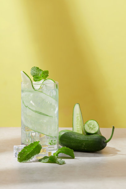 在炎热的夏天，用新鲜的黄瓜和冰块制作自己的排毒水。极简主义背景的正面视图。为报纸和杂志复印图片。图片下载
