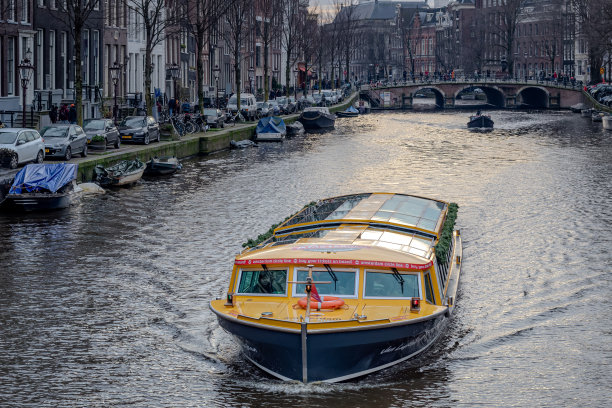 游览船沿着建筑林立的运河在阿姆斯特丹。白天在荷兰阿姆斯特丹拍摄的照片图片下载