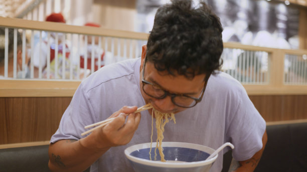 亚洲男子用筷子吃拉面。图片下载