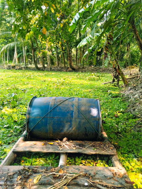 这张照片显示了一辆木车，上面有一个蓝色的桶，坐落在草地上，背景是树木。图片下载
