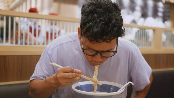 亚洲男子用筷子吃拉面。图片下载