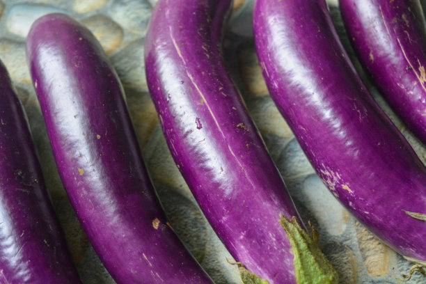 长长的紫茄子平躺在照片上面。热带国家食材图片下载