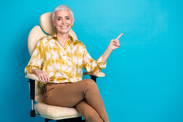 照片肖像中迷人的高级女子坐在扶手椅点空，穿着时尚优雅的衣服孤立在蓝色背景上图片下载