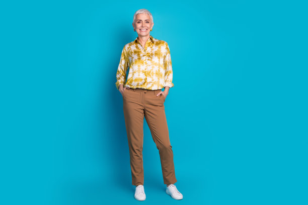 有吸引力的高级妇女的全身照片，双手口袋自信地穿着时尚优雅的衣服孤立的蓝色背景图片下载