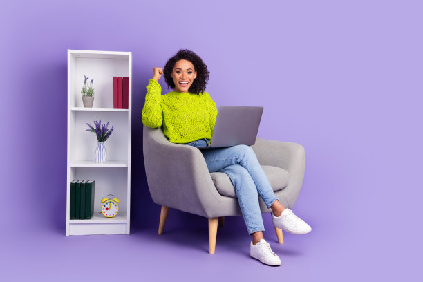 迷人的年轻女子获胜者全身照片坐在扶手椅工作办公室穿着时尚的绿色衣服孤立的紫色背景图片下载