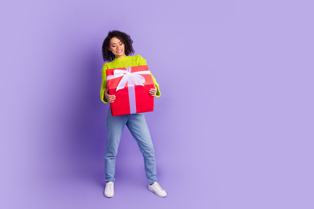 照片肖像卷发微笑的快乐女孩准备节日重红色礼盒孤立的紫色背景图片下载