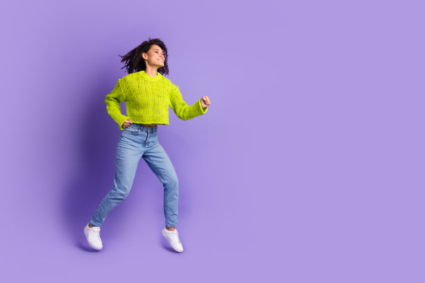 可爱的年轻女士跑步的全身照片有乐趣穿着时尚的绿色服装孤立的紫罗兰色背景图片下载