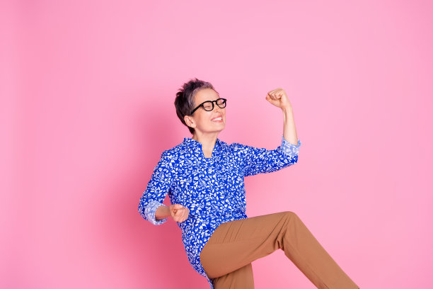 喜出望外的老人的照片，灰色的发型，穿着印花衬衫，紧握拳头，赢得了孤立的粉红色背景图片下载