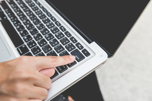 人用食指按下按钮删除键盘上的笔记本电脑。图片下载