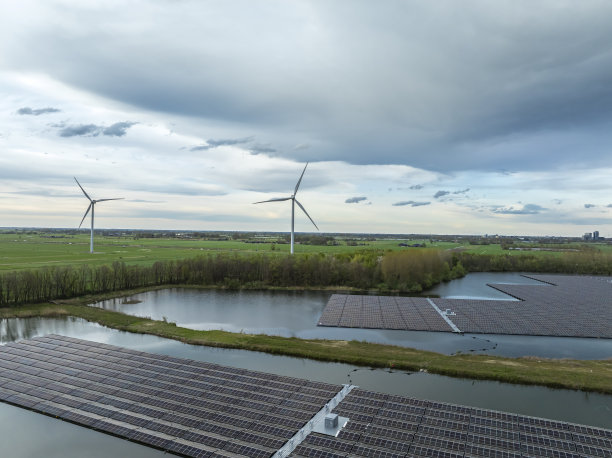 太阳能电池板漂浮在湖面上，背景是风力涡轮机图片下载