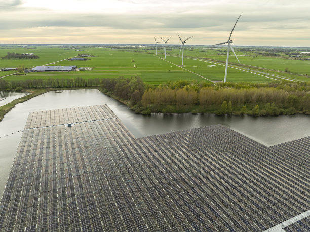 太阳能电池板漂浮在湖面上，背景是风力涡轮机图片下载