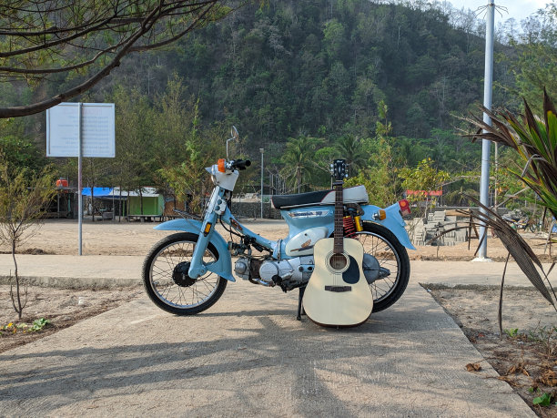 一辆旧的蓝色摩托车和一把吉他。图片下载