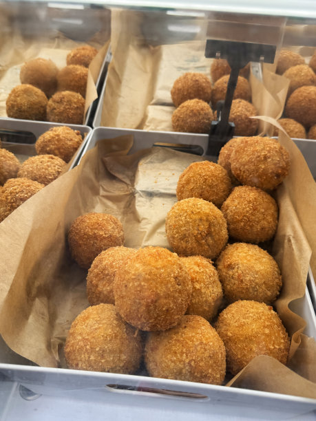 食品市场摊位的特写图片，苏格兰鸡蛋陈列在玻璃隔板后面，防油羊皮纸衬里的托盘里放着一堆煮熟的鸡蛋，包着香肠肉，裹着面包屑，零食，高架视图，重点放在前景图片下载