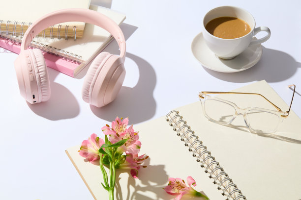 白色的桌子上有办公用品的广告横幅模板，上面装饰着一些粉红色的花和一杯早晨的咖啡。照片从上面的视图与文字的复制空间图片下载