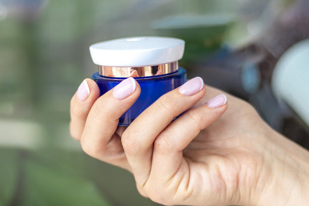 美女的手拿着一瓶护肤品的照片。时尚图片下载