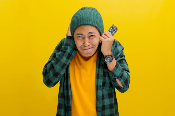 惊恐的亚洲男子拿着电视遥控器，在看恐怖电影时被跳跃吓到了图片下载