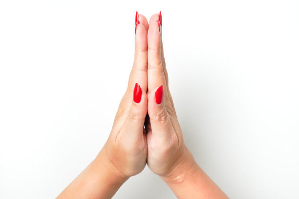 一个涂着鲜红色指甲油的女人的手形成了“双手合十”的手势，表示祈祷。孤立在白色背景上。图片下载