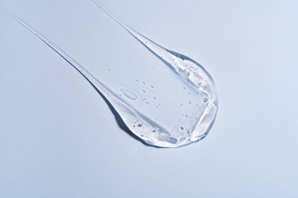 护肤凝胶，面部精华液，在蓝色背景上涂抹。透明光凝胶美容产品涂抹刷特写图片下载