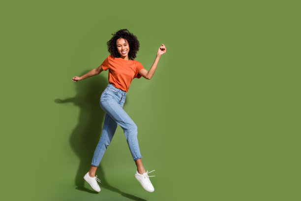 在卡其色的背景下，穿着时髦的橙色衣服参加黑色星期五运动的迷人年轻女子的全身照片图片下载